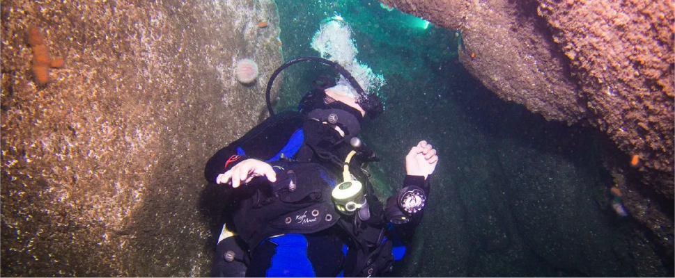 Scuba diver under water between two rocks