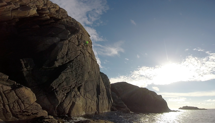 Cliff climber scaling a cliff above the ocean