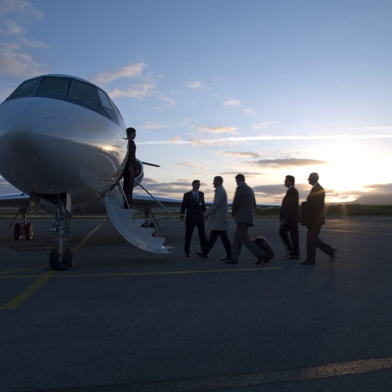 Group of business men on airport apron met by cabin crew for a private flight